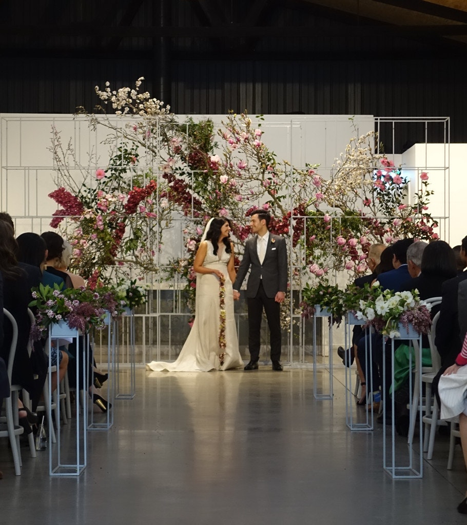 Wedding couple holding hands at the top of the aisle.